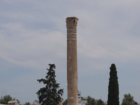 View of a solitary ancient marble column of the Temple of Olympian Zeus against a cloudy sky in Athens, Greece.