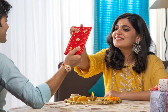 A PLAYFUL BROTHER TEASING SISTER WITH RAKSHABANDHAN GIFT