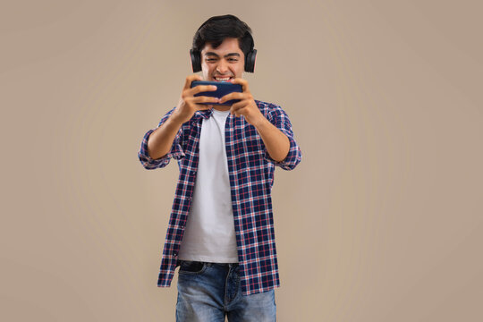 AN ENTHUSIASTIC TEENAGER PLAYING VIDEO GAME ON MOBILE PHONE