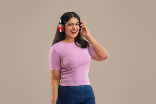 A HAPPY YOUNG WOMAN LISTENING TO MUSIC ON HEADPHONES