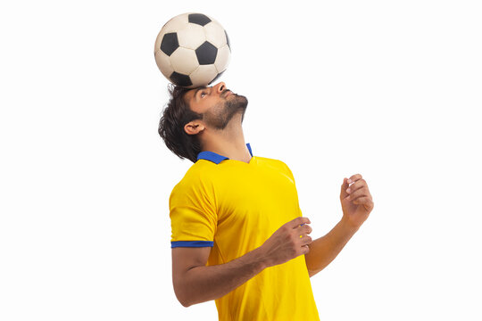 A FOOTBALL PLAYER BALANCING BALL ON HIS HEAD WHILE PRACTICING