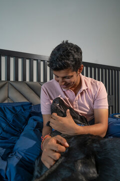 Young man spending time with his pet dog in his house.