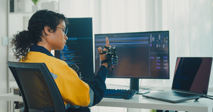 Young Black female engineer coding AI robot arm in modern laboratory. Robotics, artificial intelligence, technology, stem, future, innovation, diversity, automation, machine learning concept.