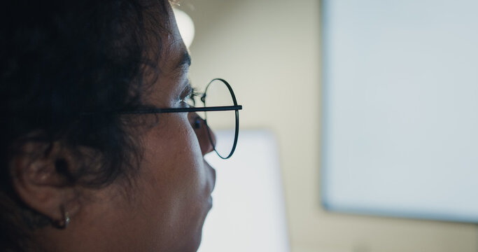 Close-up Black female programmer with code reflection in glasses working late in home office at night. Cybersecurity, AI algorithm, Network security, software developer, serious face, burnout concept.