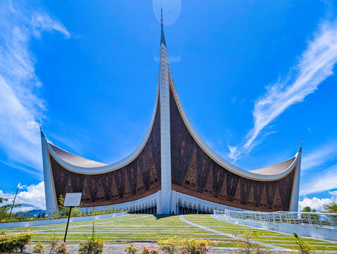 View of the Great Mosque of West Sumatra with its distinctive curved roof architecture under a clear blue sky in Padang, West Sumatra, Indonesia.