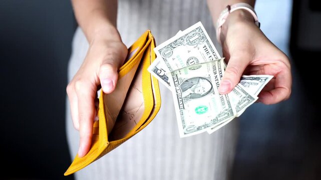 Close-up of female hands showing open empty wallet and last usd banknotes. Inflation, poverty and spending money concept.