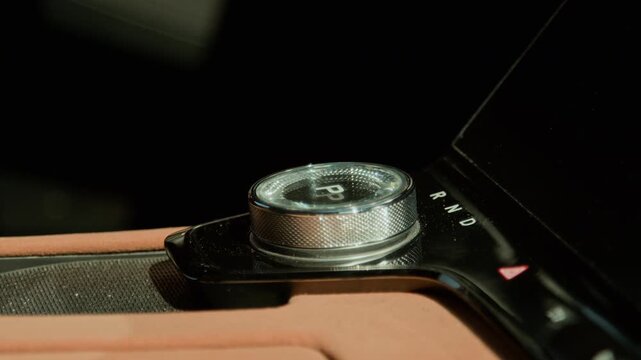 Rotary gear selector in modern luxury vehicle glowing on center console. Clip is suitable for automotive technology advertisements, electric car reviews, and transportation industry marketing