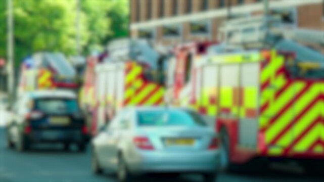 Busy city road with blurred fire trucks and cars during emergency response. Multiple rescue vehicles parked near urban buildings. Accident disaster and first responder concept