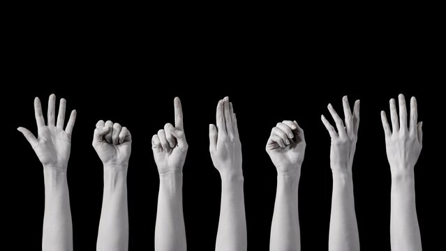 Seven human hands raised in various gestures against a black background