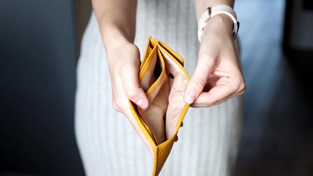 Close-up of female hands showing open empty wallet. Broke, bankruptcy, debt, financial crisis, poverty and inflation concept.