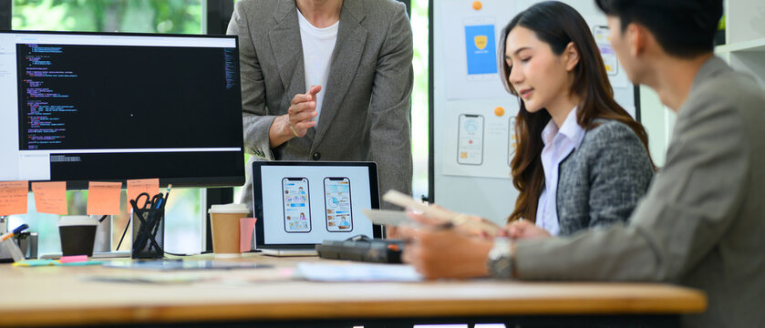 Closeup Developer Team Brainstorming UI UX App Design in Modern Office Meeting with Code on Screen