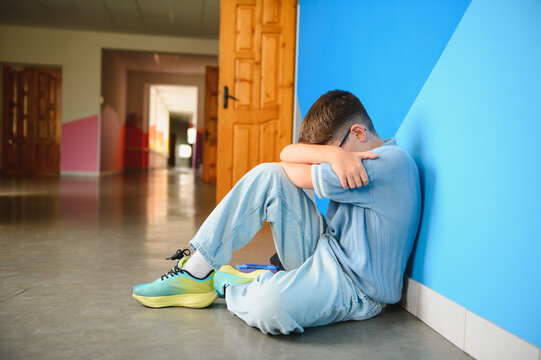 Boy hiding face feeling sad from bullying at school