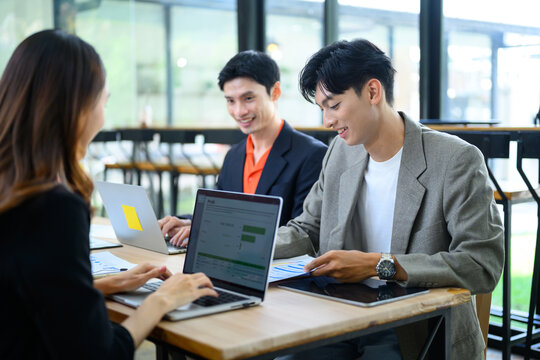 Young Asian Business Team Collaborating with Laptops in Modern Co working Office Space