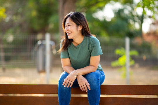 Asian woman sitting on bench enjoying peaceful moment