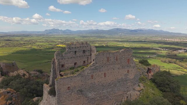 Castello di Acquafredda Atop Hill Near Siliqua In Southern Sardinia, Italy, Surrounded By Rugged Terrain And Rural Countryside. Aerial Wide Shot