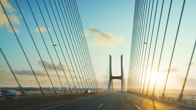 Driving on Vasco da Gama cable stayed bridge at sunset view from car camera, Lisbon, Portugal. Longest bridge in Europe over Tagus river. 