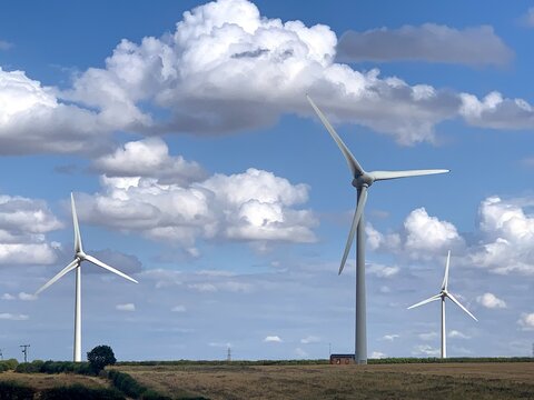 View of the Burton Wold wind farm with turbine 1 standing tall in a field under a blue sky with white clouds in Burton Latimer, England, United Kingdom.