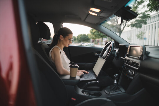 Businesswoman working on laptop in parked car