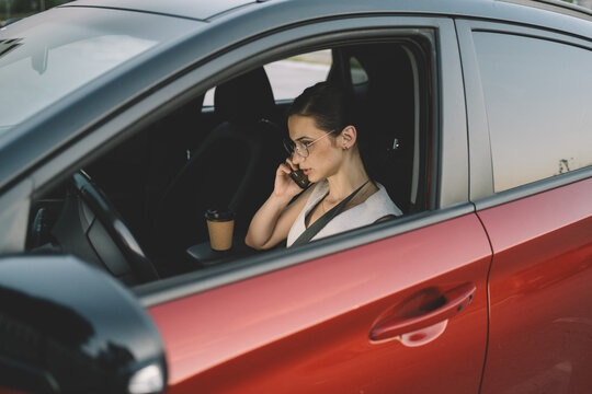 Businesswoman talking on a smartphone while sitting in the front seat of a parked car