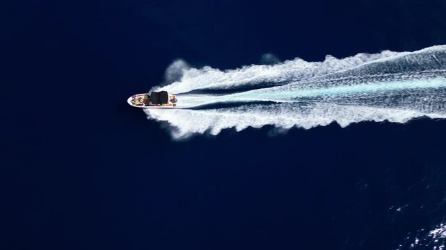 Three speedboats race across the deep blue adriatic sea, leaving white trails in their wake. The vibrant summer scene captures the thrill of coastal tourism and beachside adventures.