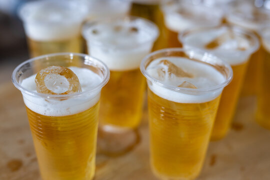 Many plastic cups full of beer with foam. Beer in disposable cups filling a table, ready for a party, celebration, or casual gathering, creating a festive atmosphere.