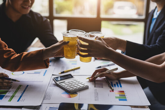 Celebrate financial and business success with your partners. Colleagues toasting drinks together, celebrating business achievement with refreshing beverages during an office party or happy hour.
