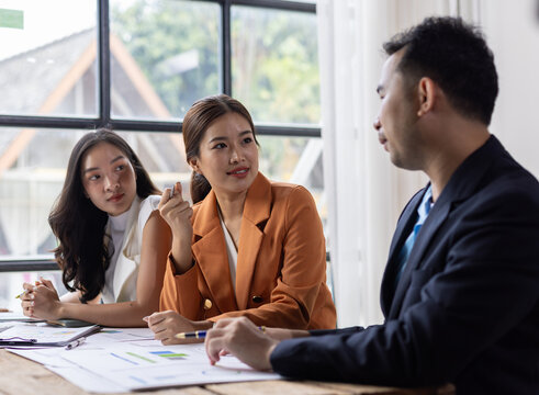Asian business team discussing project during meeting in office. Professional Asian business people collaborating and sharing ideas, analyzing reports and data during a corporate meeting.