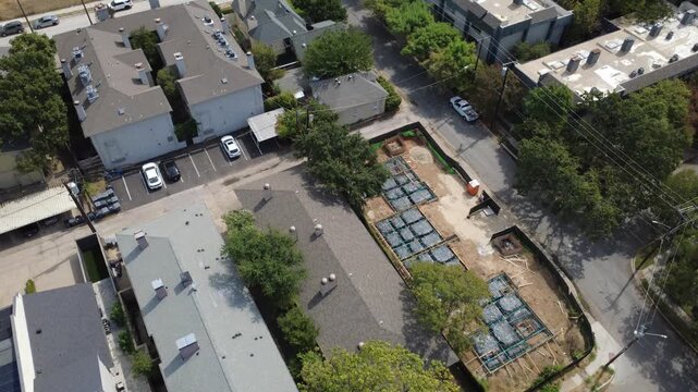 Elongated foundation footings occupy cleared residential parcels near Reagan Street in Dallas. Adjacent multi family parking courts mark steady infill growth across DFW Metroplex, Texas
