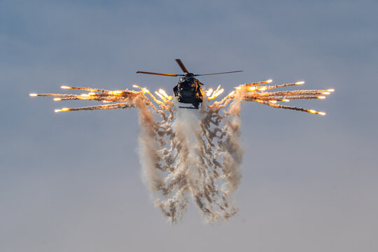 View of an NH-90 military helicopter releasing flares in a symmetrical pattern during an airshow in Leszno, Greater Poland Voivod, Poland.