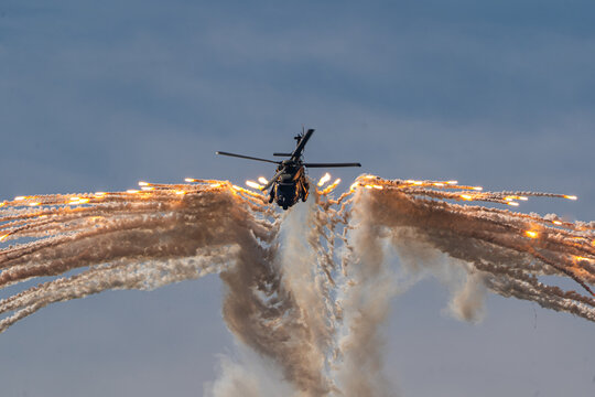 View of an NH-90 helicopter releasing flares during an airshow display against a cloudy sky in Leszno, Greater Poland Voivod, Poland.