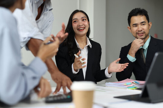 Business colleagues collaborating during a professional office meeting. Asian business people working together in office workplace, teamwork and cooperation.