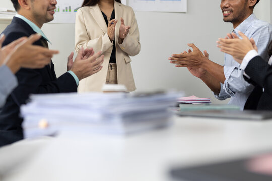 Business professionals in a meeting room feeling happy while applauding and celebrating success and achievement after a business presentation.