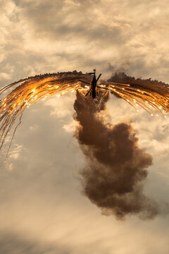 View of an NH-90 helicopter releasing bright flares during an airshow display against a dramatic cloudy sky in Leszno, Greater Poland Voivod, Poland.