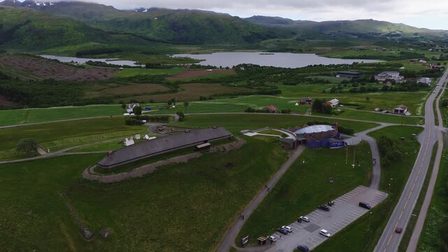 Aerial view shows the reconstructed chieftain longhouse and visitor center at Lofotr Viking Museum in Borg surrounded by hills and lakes in Lofoten, Norway.