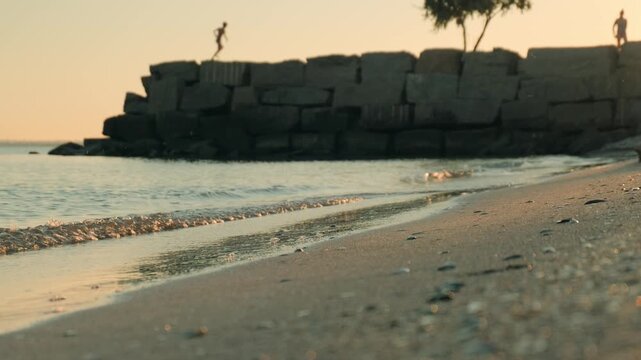 Calm evening sea surf, someone running in the background in defocus
