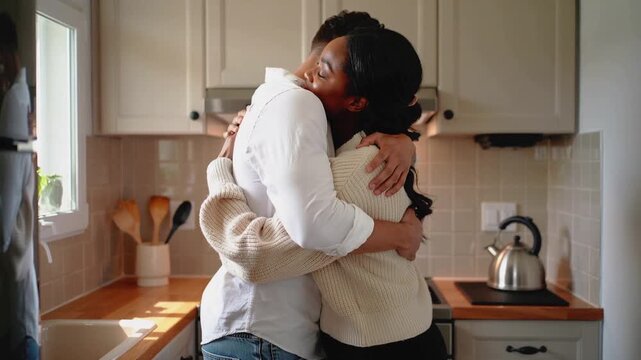 Touching foreheads, two adults hugging in compact kitchen near kettle, seeking comfort