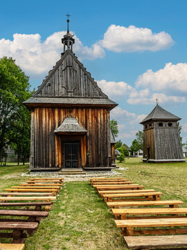 Historic Wooden Church With Outdoor Benches And Separate Bell Tower Under Blue Summer Sky