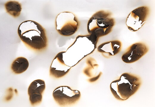 Collection of burnt holes in piece of double paper isolated on white background