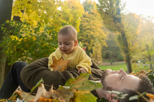 Father and Baby Enjoying Autumn Leaves Copy Space