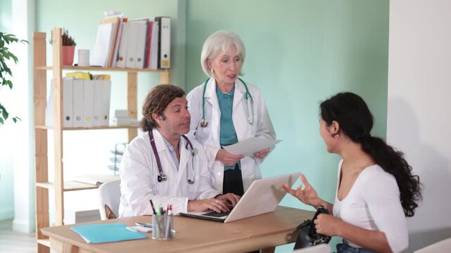 Polite male and female doctors explaining diagnostic results to woman patient inside clinic office. High quality 4k footage