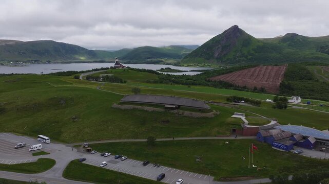 An aerial camera flies over the reconstructed chieftain longhouse at Lofotr Viking Museum in Borg, Vestvagoy, Lofoten, Norway on an overcast summer day.
