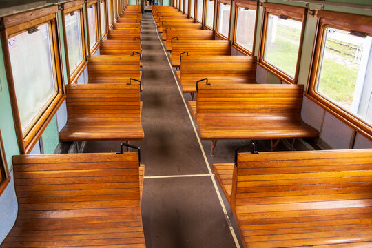 View of the interior of a vintage train carriage featuring polished wooden benches and a central aisle in the Railway Park in Vilnius, Vilniaus apskritis, Lithuania.