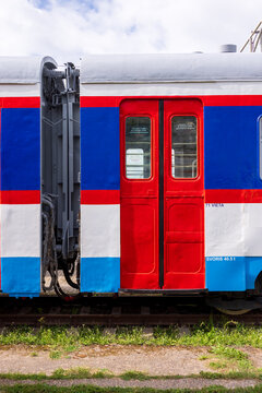 View of a red, blue, and white train carriage with bright red doors parked on tracks in Railway Park in Vilnius, Vilniaus apskritis, Lithuania.