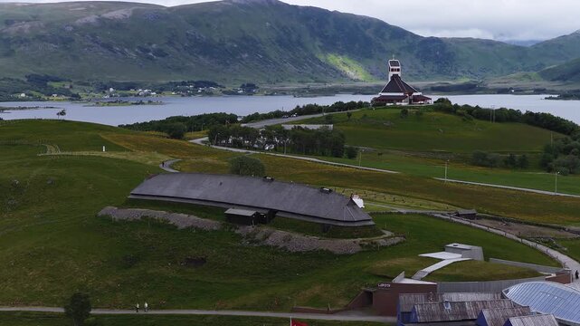 Aerial view captures the reconstructed chieftain longhouse at the Lofotr Viking Museum alongside Borge Church on the hills of Lofoten in Borg, Norway.