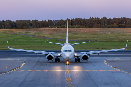 View of a commercial airplane taxiing on the runway at Vilnius International Airport during dusk in Vilnius, Vilniaus apskritis, Lithuania.