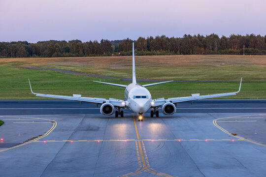 View of a commercial passenger airplane taxiing on the runway at Vilnius International Airport during the golden hour in Vilnius, Vilniaus apskritis, Lithuania.