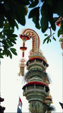 Tall decorative bamboo pole penjor erected for Galungan Hindu festival along street, Bali, Indonesia
