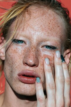 Close-up freckled redhead beauty portrait with green manicure for makeup and skin care editorial and beauty background
