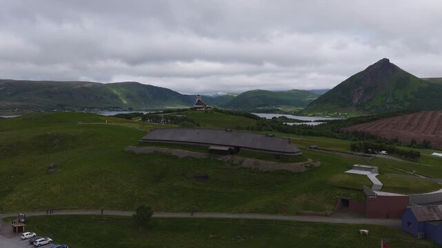 An aerial view captures the reconstructed chieftain longhouse at Lofotr Viking Museum in Borg, Vestvagoy, set against mountains and lakes in Lofoten, Norway.