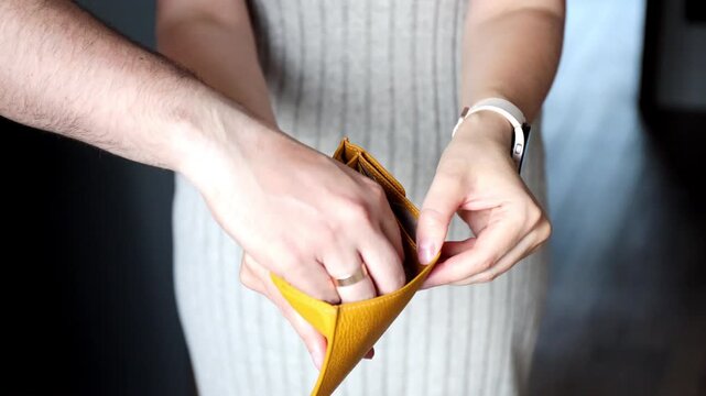 Female hands showing open empty wallet and last banknotes taken by another hand. Inflation, poverty and spending money concept.